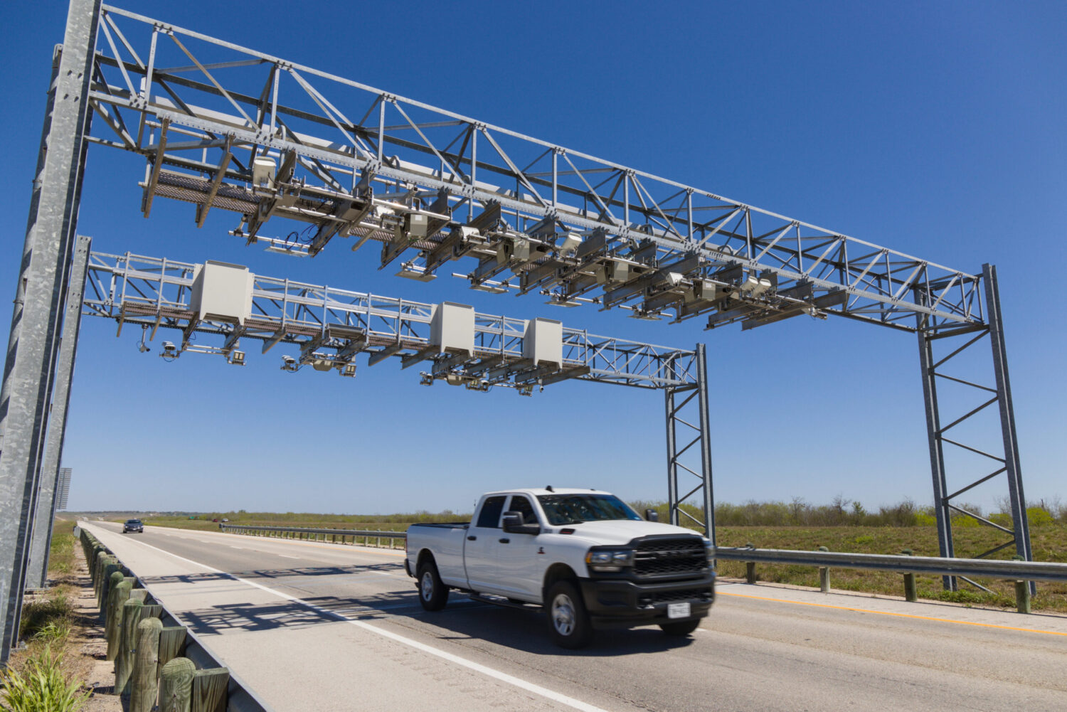 White pickup truck driving under a toll gantry on SH 130 in Texas