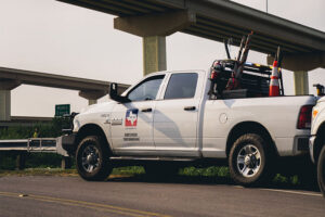 An SH 130 Concession Company service truck parked on the highway shoulder beneath an overpass