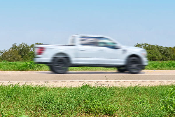 Side view of a white truck driving on SH 130