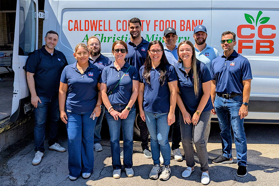 SH 130 staff members posing together in front of a Caldwell County Food Bank van during a volunteer event.