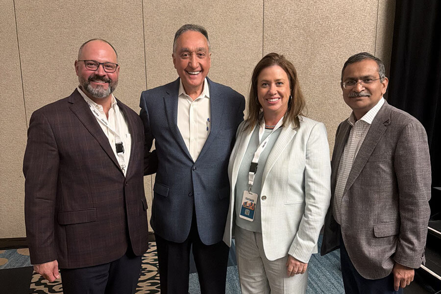 Four professionals posing together at a chamber of commerce conference event.
