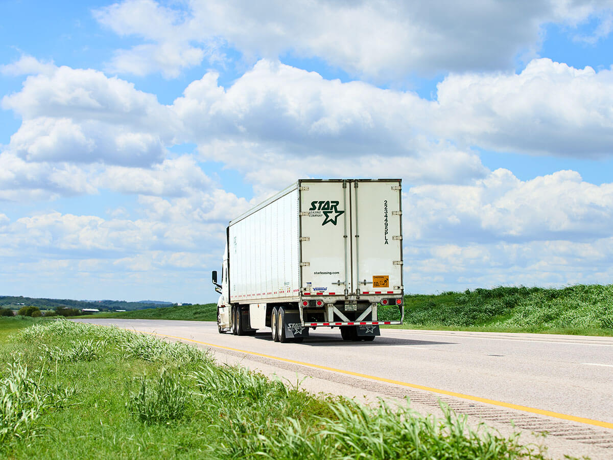 Semi-truck hauling freight down SH 130 under a partly cloudy Central Texas sky.