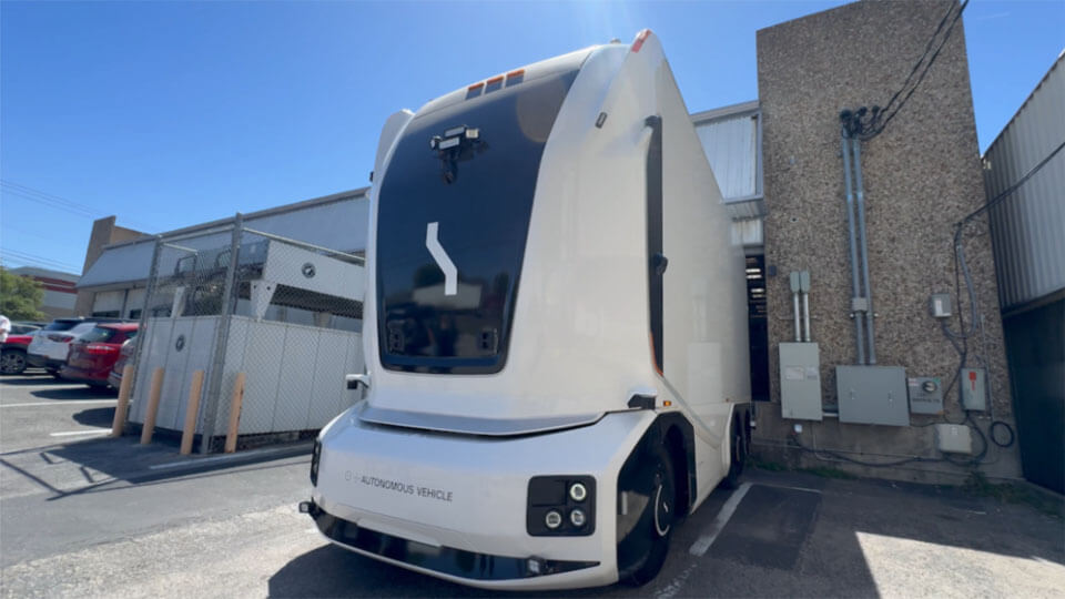 A white cabless autonomous freight truck with front-mounted sensors.