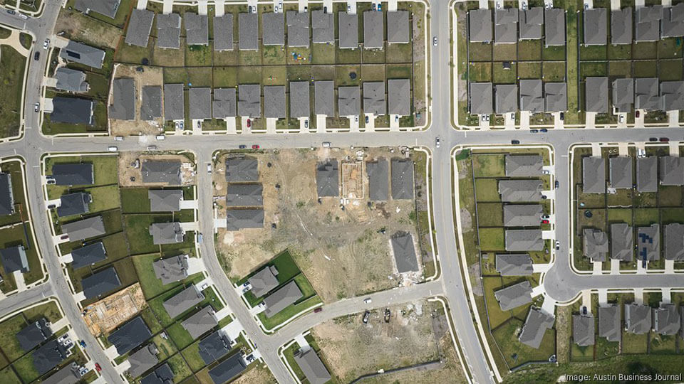 Aerial view of a suburban neighborhood with rows of homes and new construction underway on undeveloped lots.